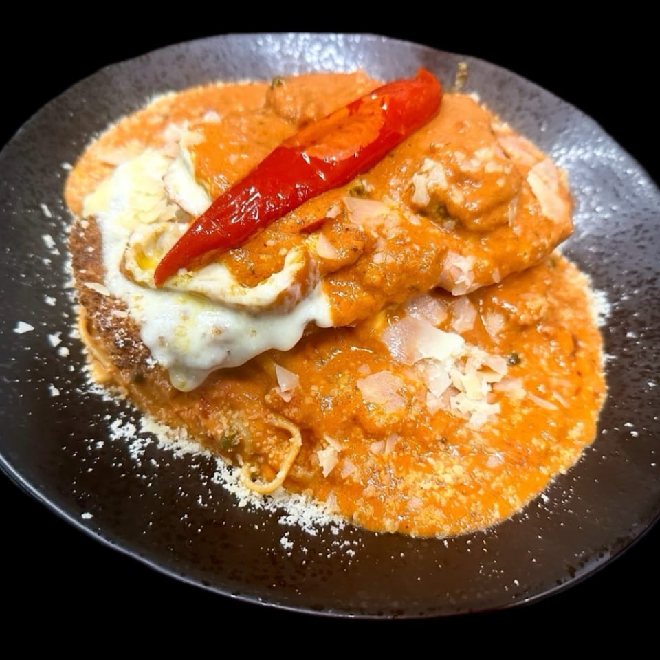 Pasta with creamy orange sauce, melted cheese, grated parmesan, and a red chili pepper.